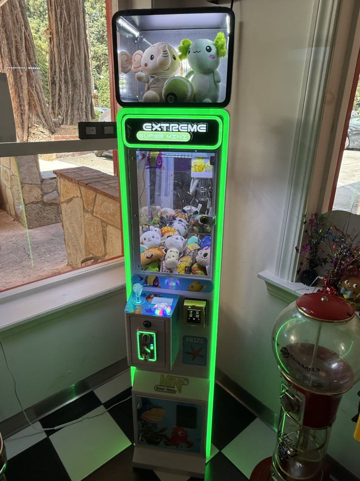 A green-lit California Claw machine in a diner window corner